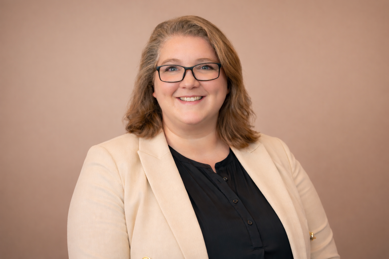 Smiling professional woman in beige blazer and glasses