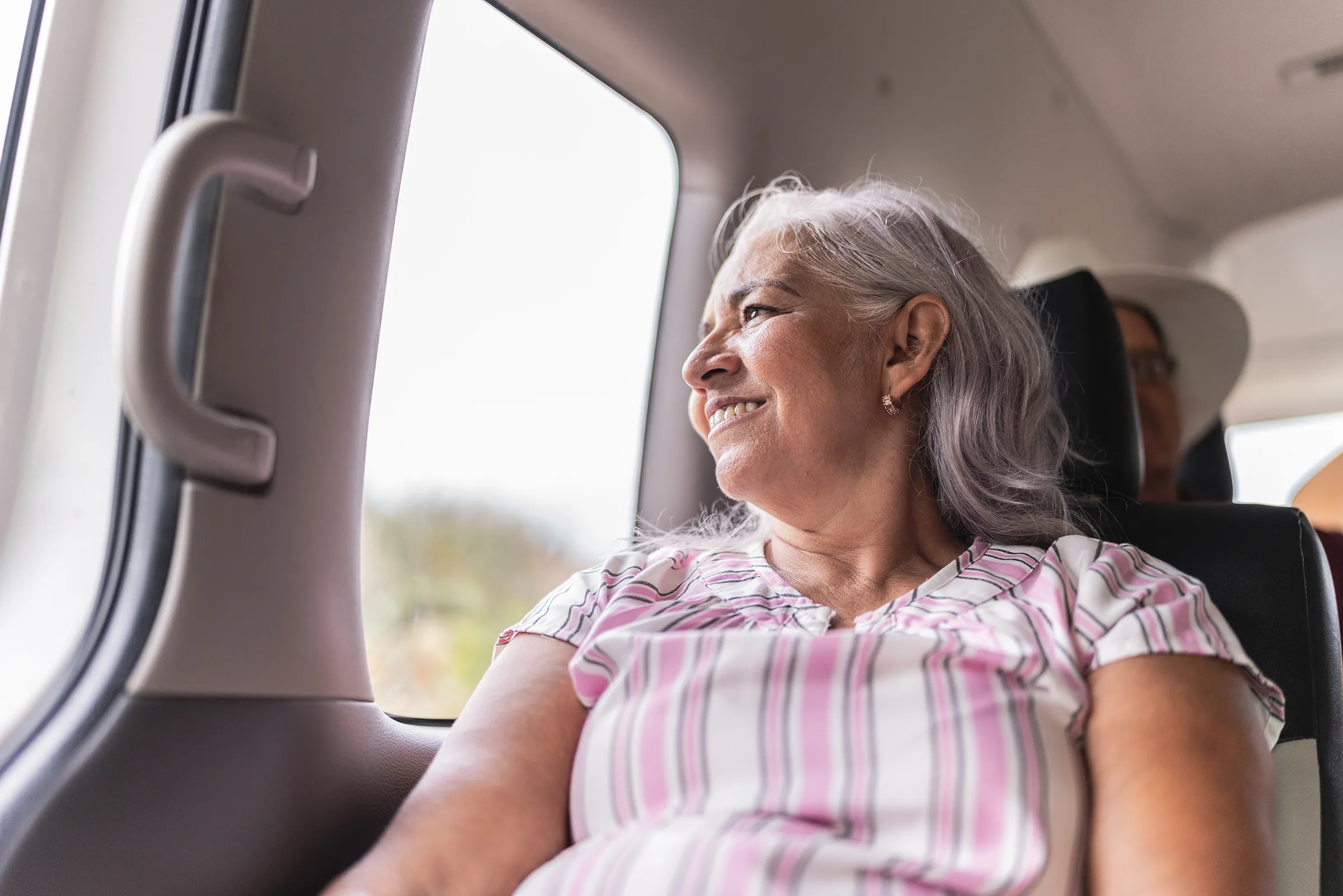 Resident sitting inside a vehicle looking out the window with a smile, capturing a moment of community lifestyle.