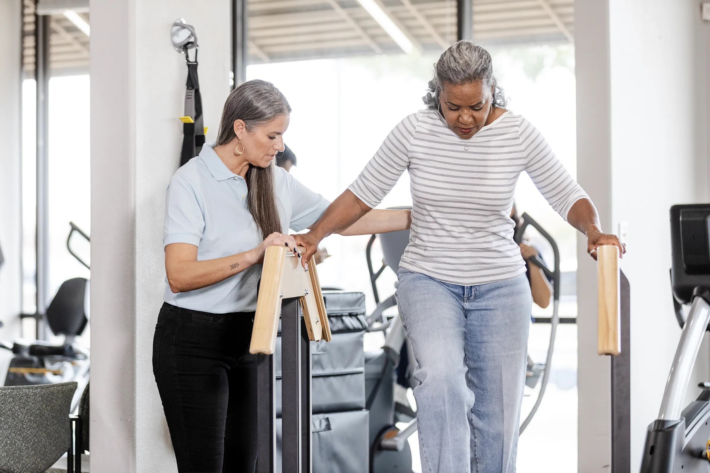 Physical therapist assisting woman walking in rehab clinic